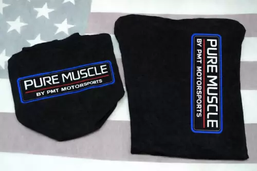 Two black clothing items, each with a blue-bordered logo reading 'PURE MUSCLE BY PMT MOTORSPORTS' set on a light American flag background.